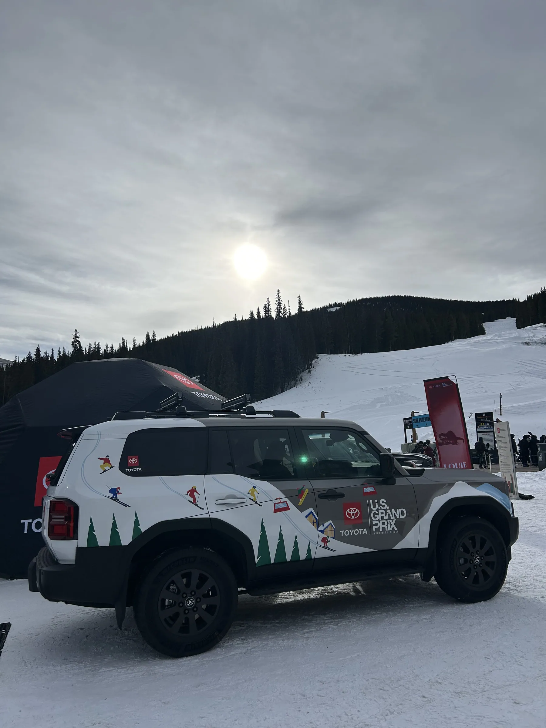 Wrapped Toyota SUV silhouetted against low winter sun on the mountain