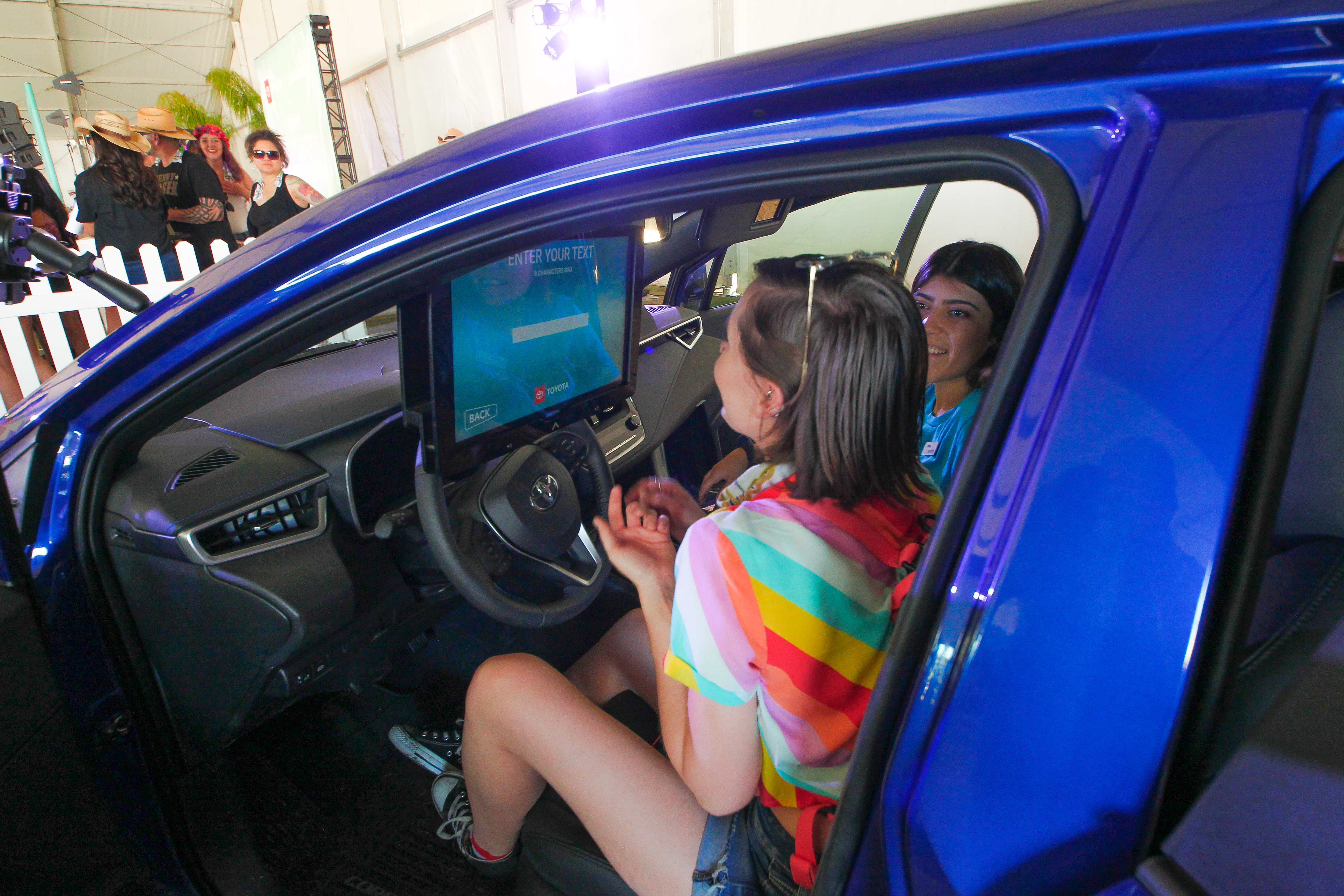 Guests hanging out inside a blue Toyota Corolla at Stagecoach