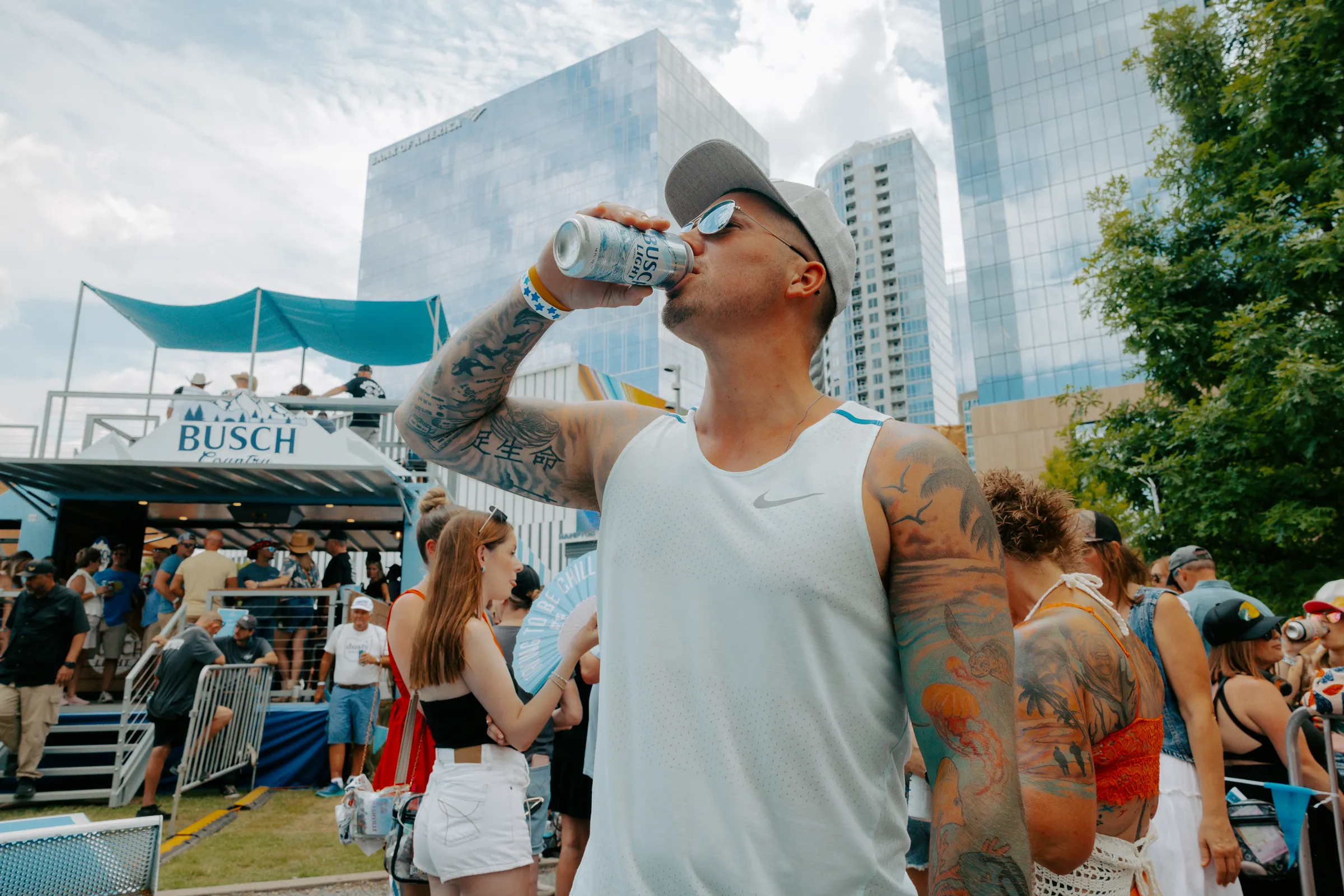 Guest drinking a Busch Light with the Nashville skyline behind the activation deck