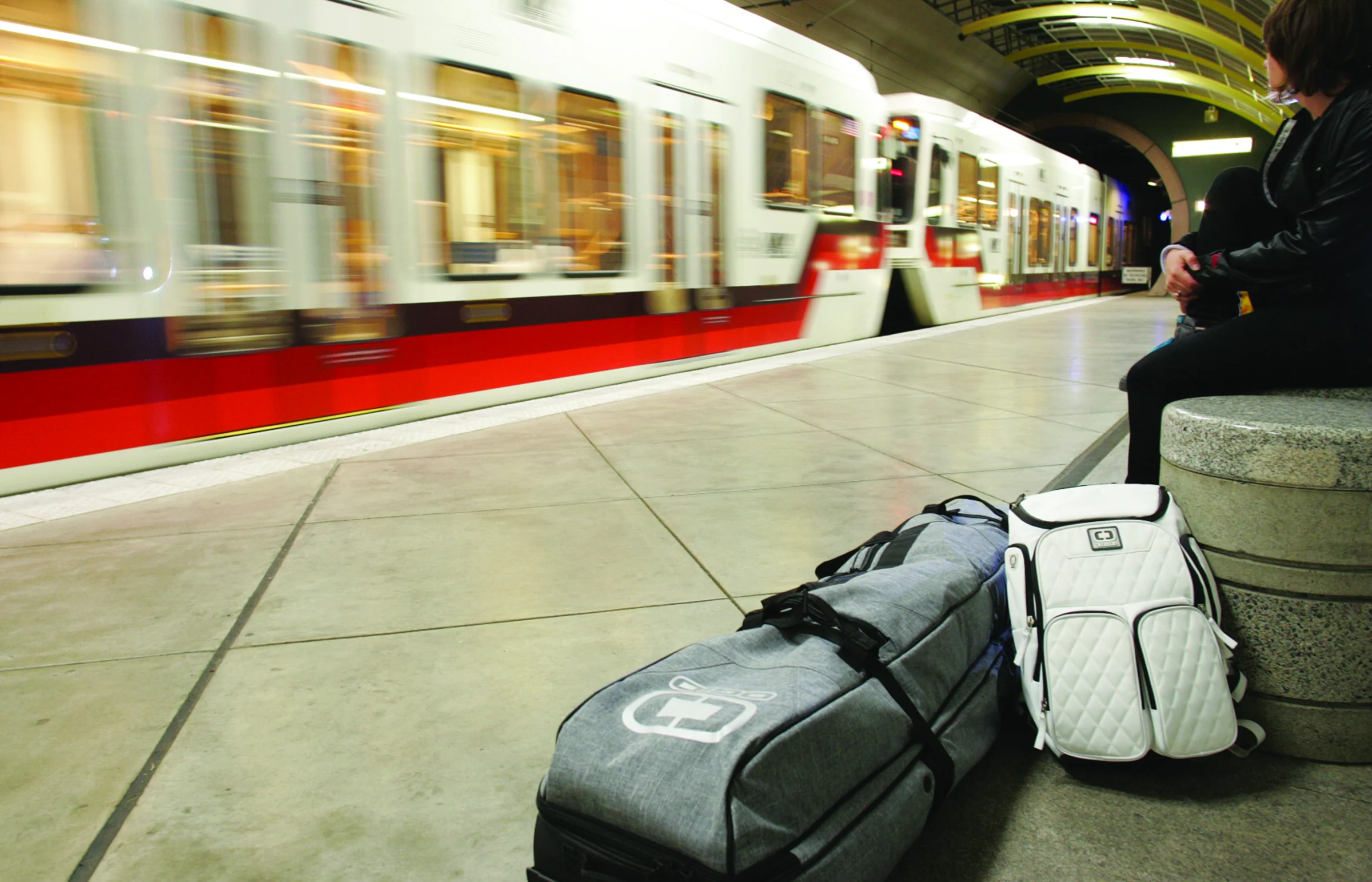 OGIO travel bags photographed on a transit platform as a train passes