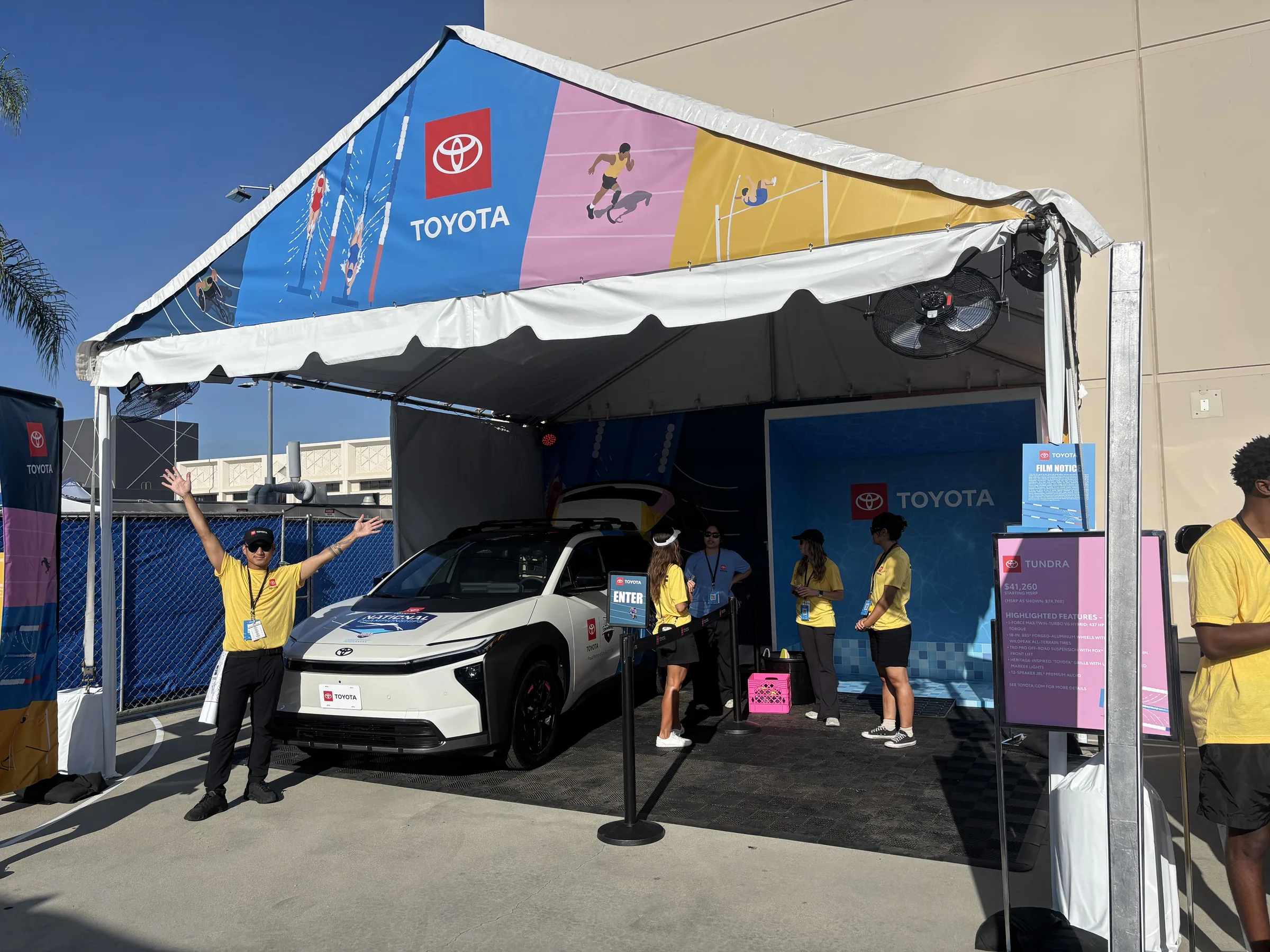 Toyota swim activation tent with a vehicle on display beneath printed canopy graphics
