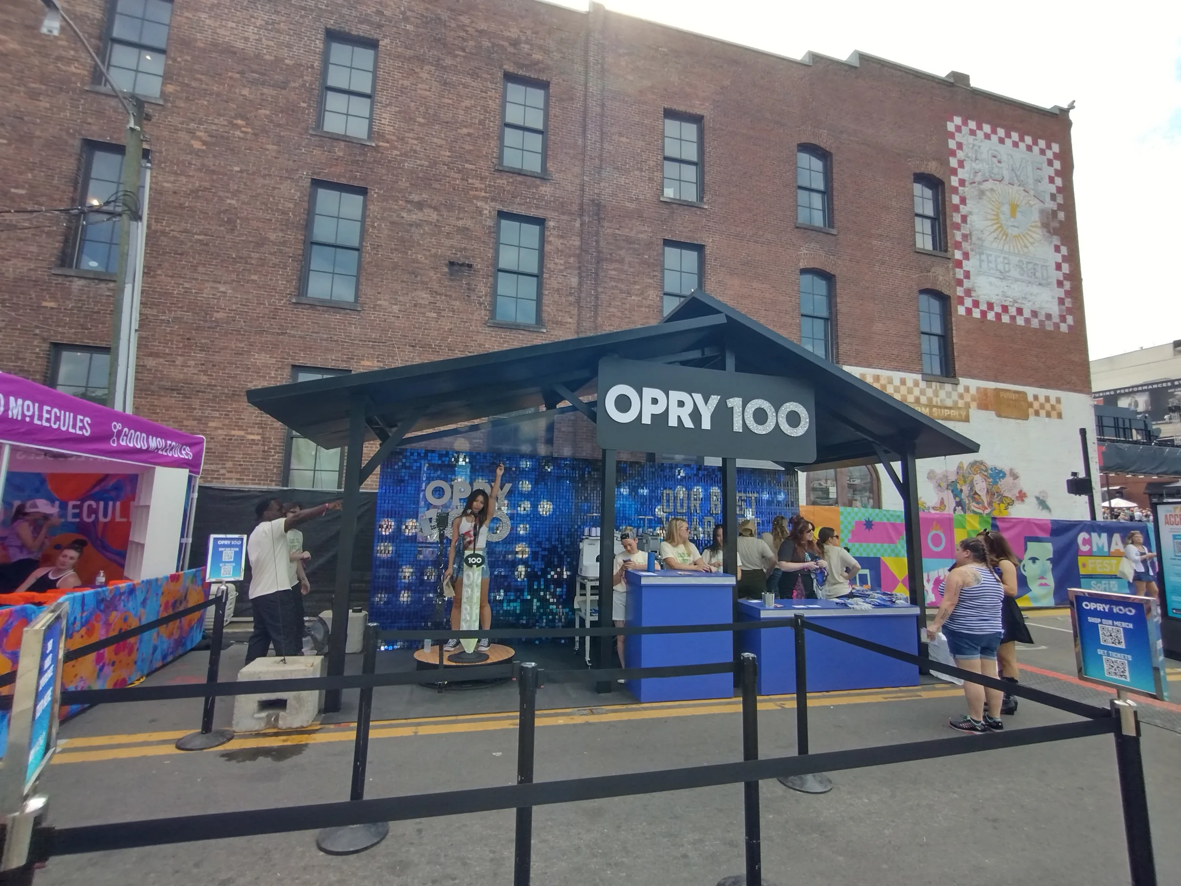 Opry 100 booth build in daylight with wood-framed graphics and guest stations