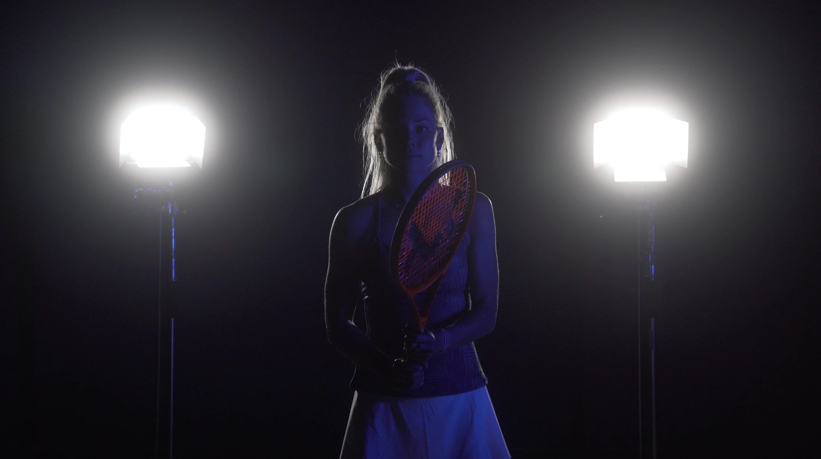 Völkl athlete lit from both sides in near darkness, holding a red Vostra racket