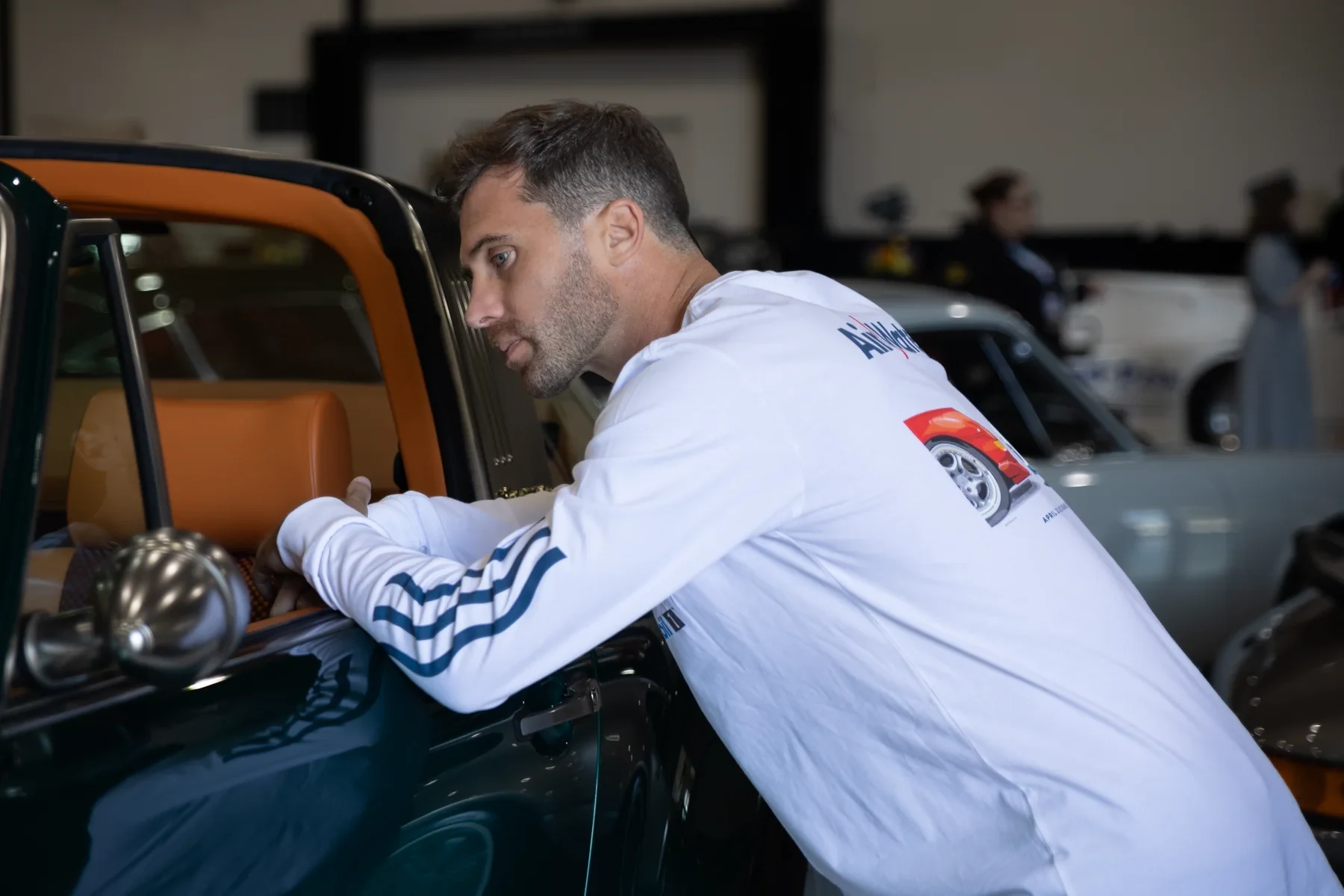 Attendee in LUFT apparel leaning over an air-cooled Porsche in the paddock