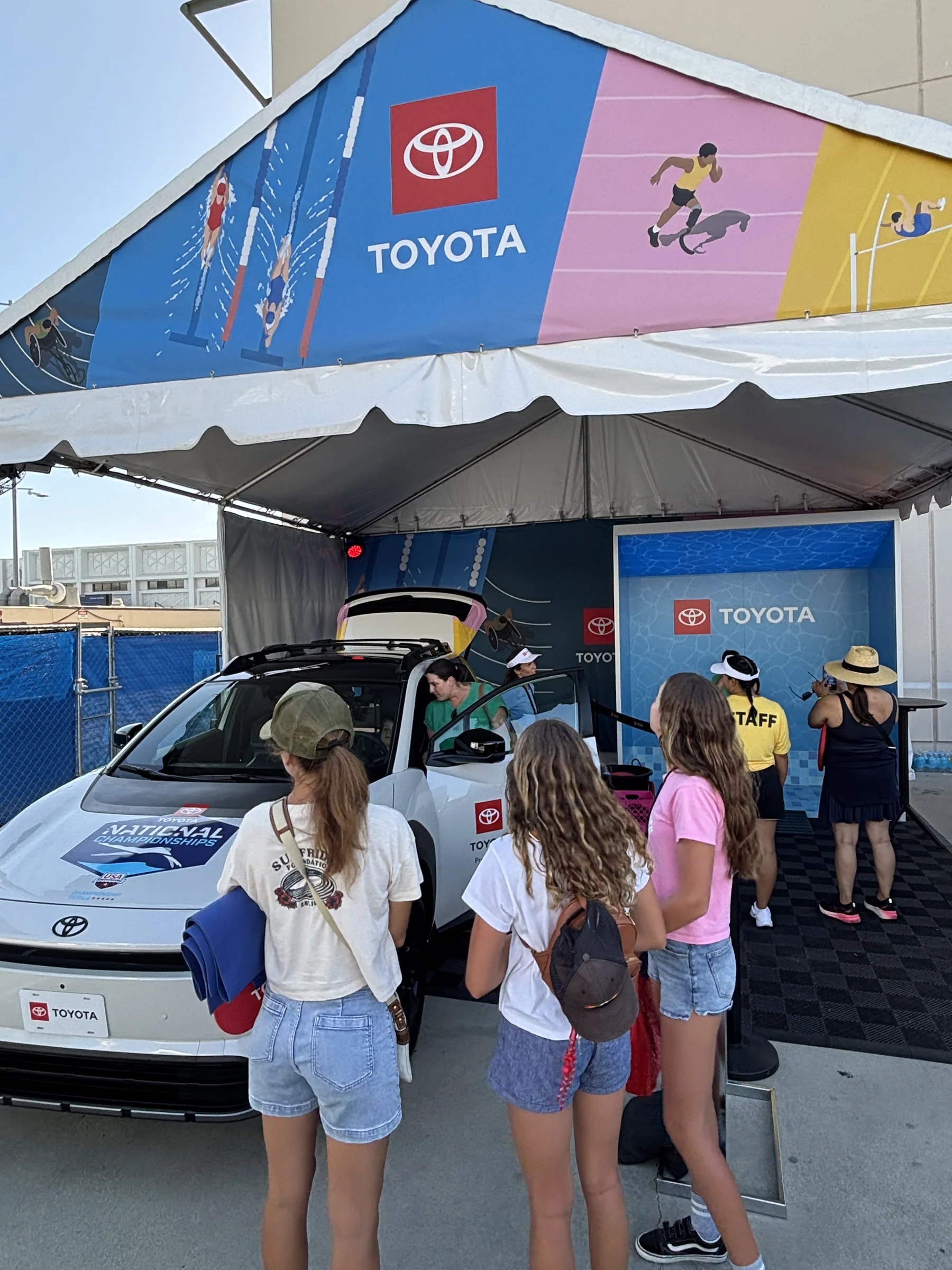 Guests gathered around a Toyota vehicle inside the swim activation tent