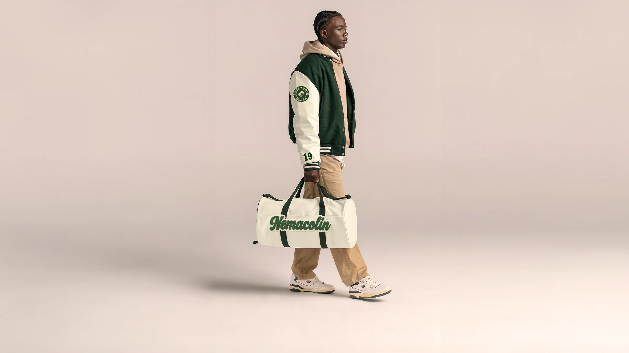 Model carrying a Nemacolin heritage duffel bag against a soft studio backdrop