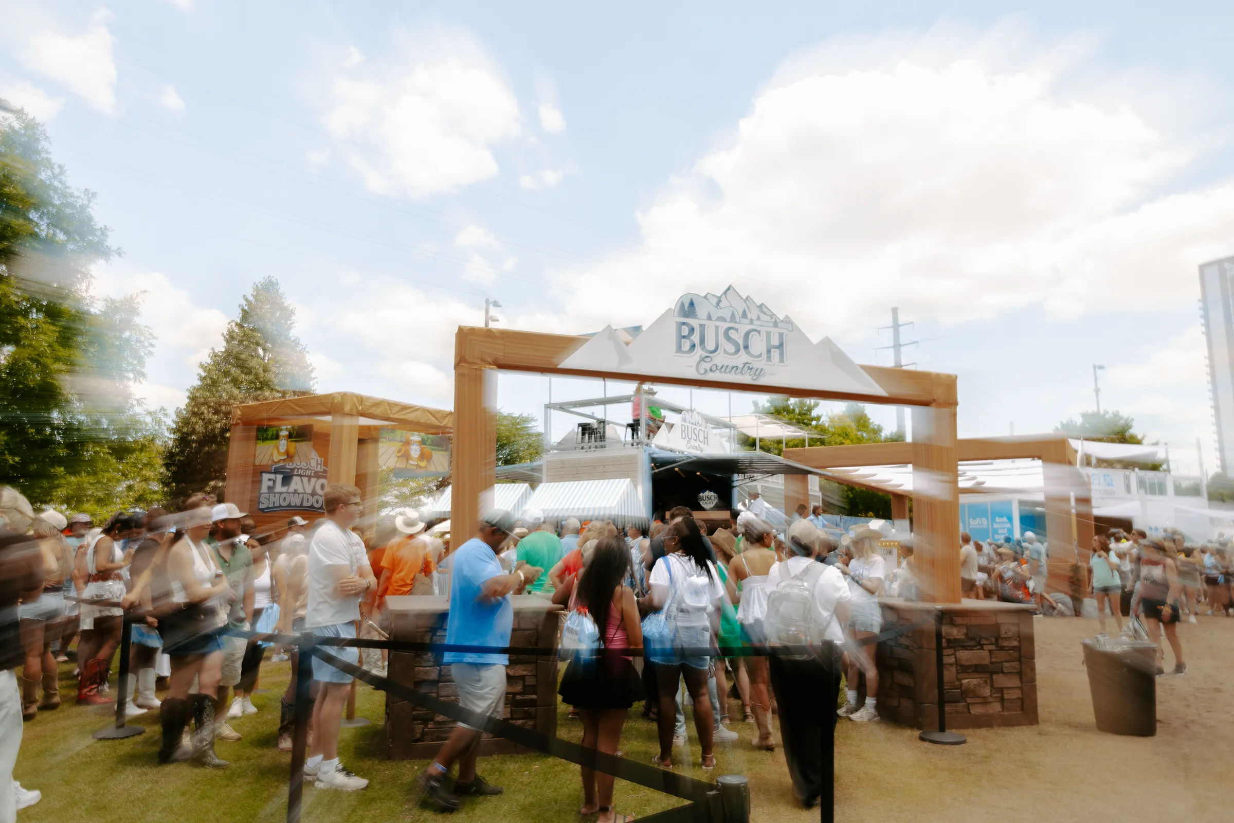 Guests moving through the Busch Country entry under the timber arch and sail-cloth canopies